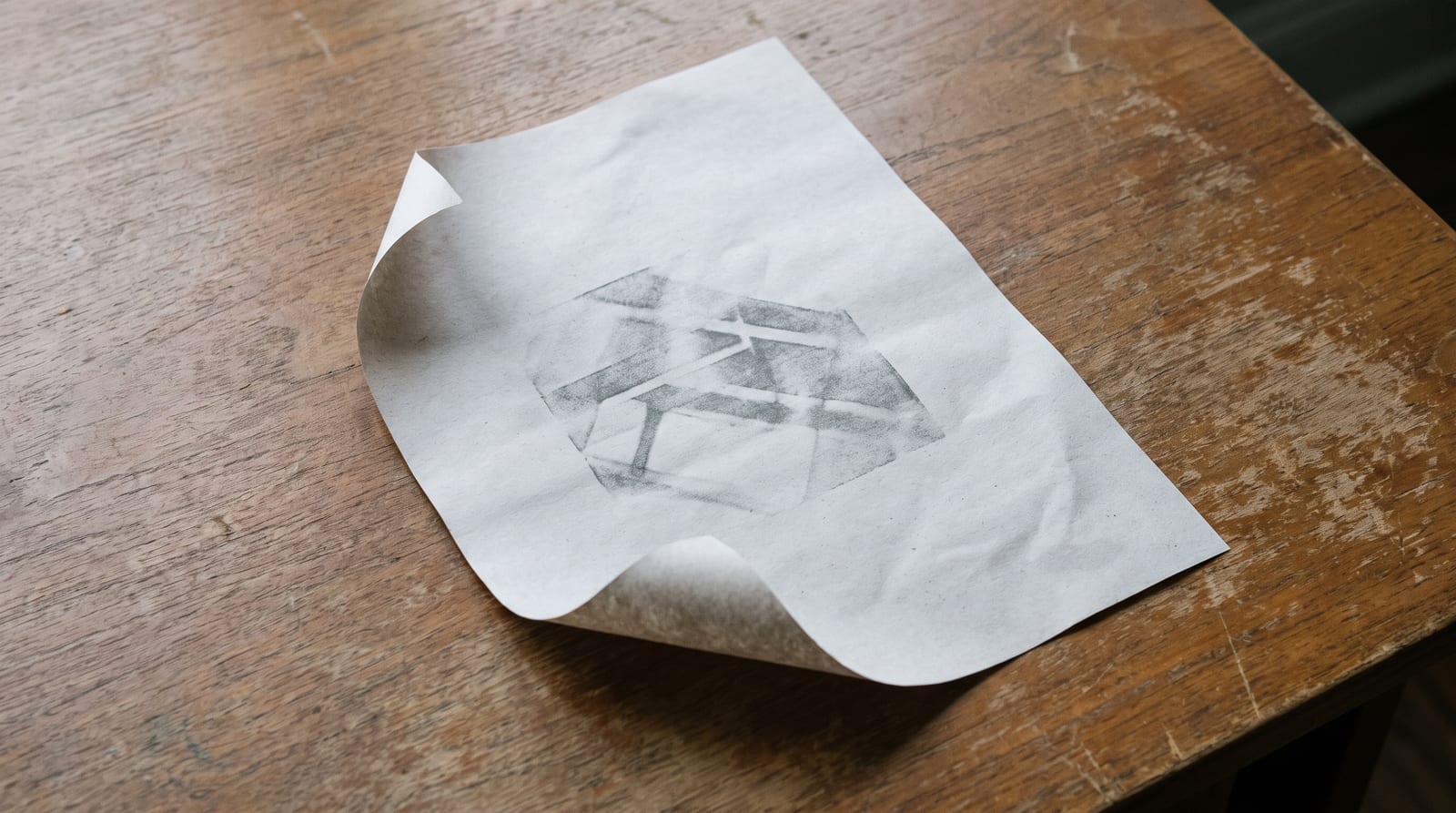 A single printed web page on a desk with a faint gray reviewed ink-stamp impression, one corner lifted